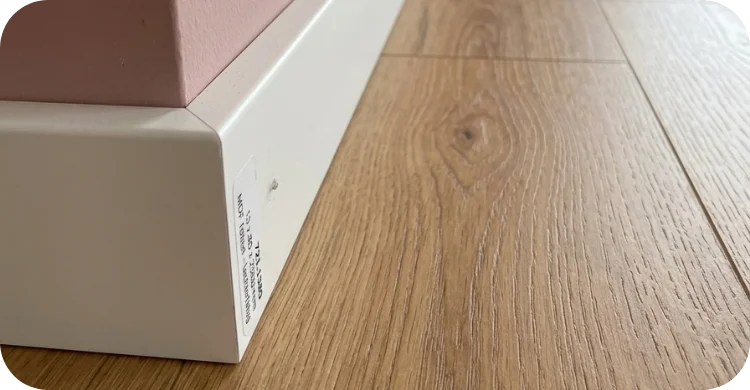 Weiße Fußleiste an Wand mit modernem Holzfußboden sauber verlegt