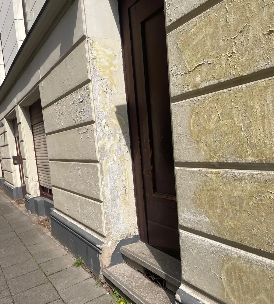 Kölner Altbaufassade vor der Sanierung mit Rissen und abblätterndem Putz