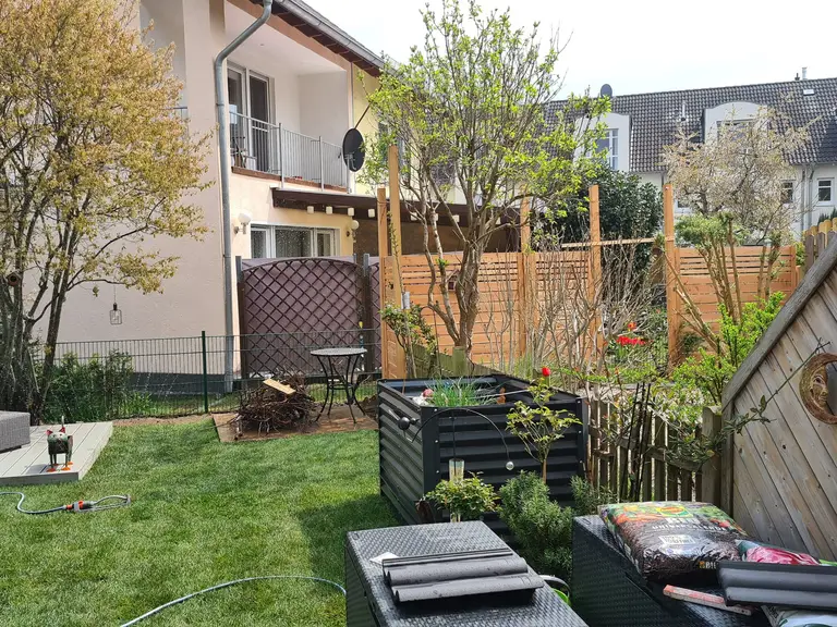 Angelegter Garten mit Hochbeeten, frischem Rasen und Sichtschutz