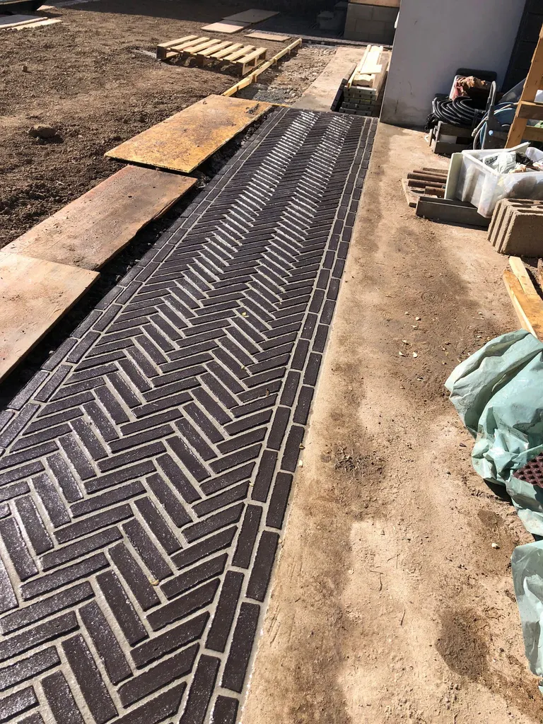 Fertig verlegter Gartenweg im Fischgrätverband aus dunklem Klinker
