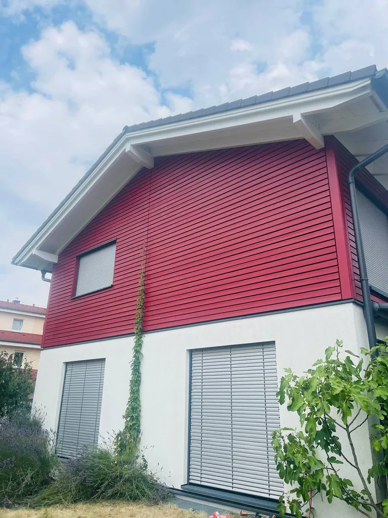 Rot gestrichene Holzfassade eines Wohnhauses nach dem Anstrich