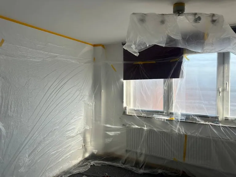 Raum in Köln vor dem Streichen: Fenster, Heizkörper und Boden sorgfältig mit Folie abgedeckt