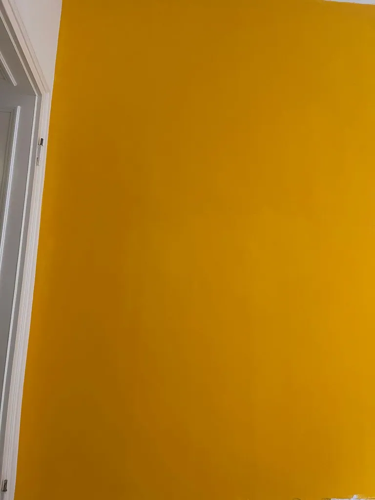 Kräftig gelb gestrichene Wand mit präziser Kante zur weißen Decke