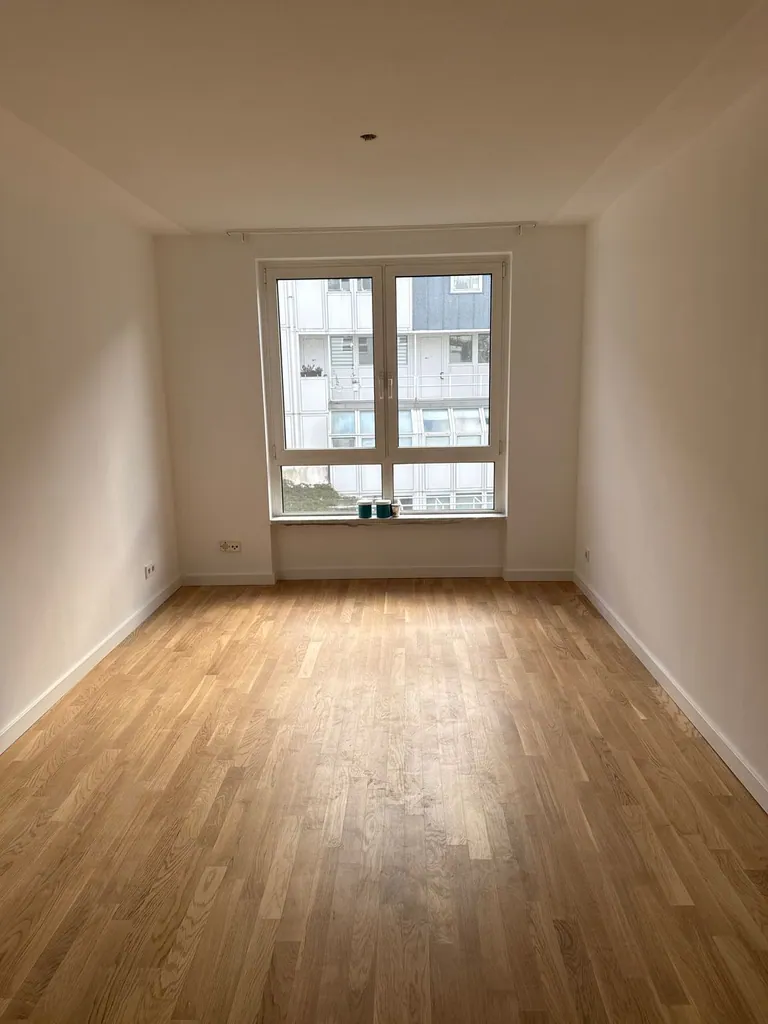 Komplett renoviertes Zimmer mit weißen Wänden und frischem Parkett in Köln