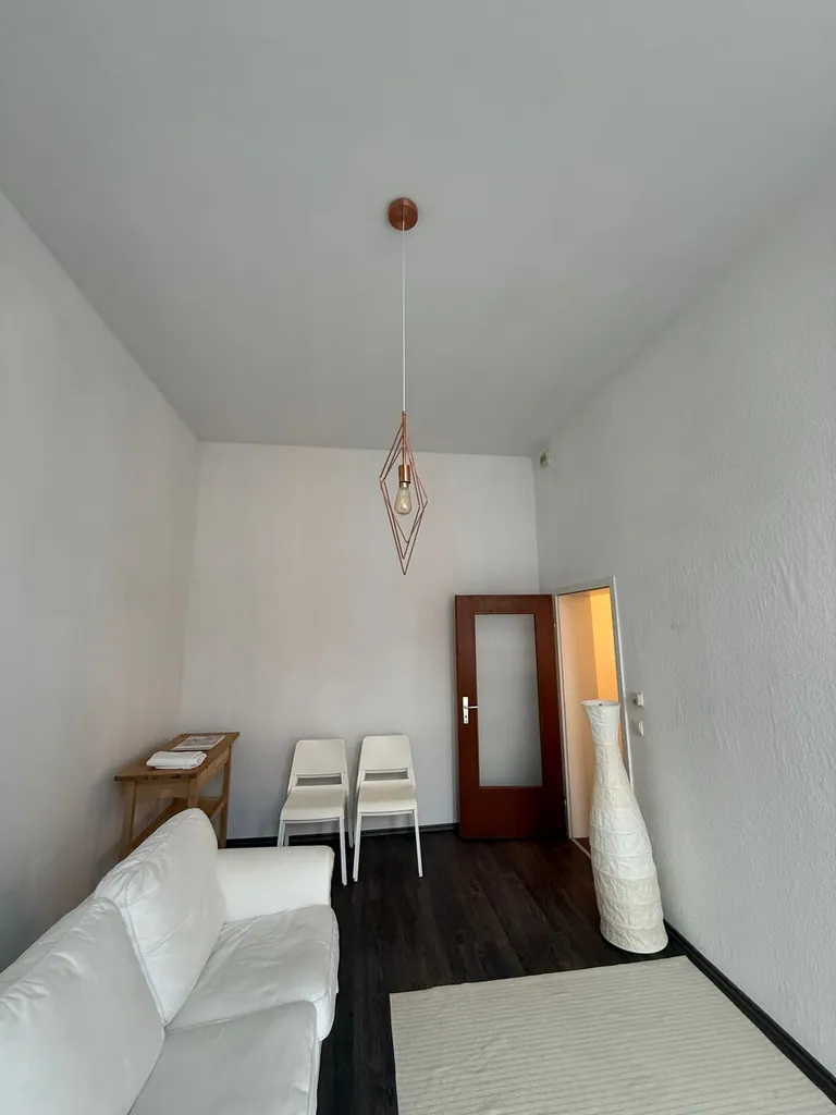 Frisch renoviertes Wohnzimmer mit weißem Sofa und dunklem Vinylboden in Köln