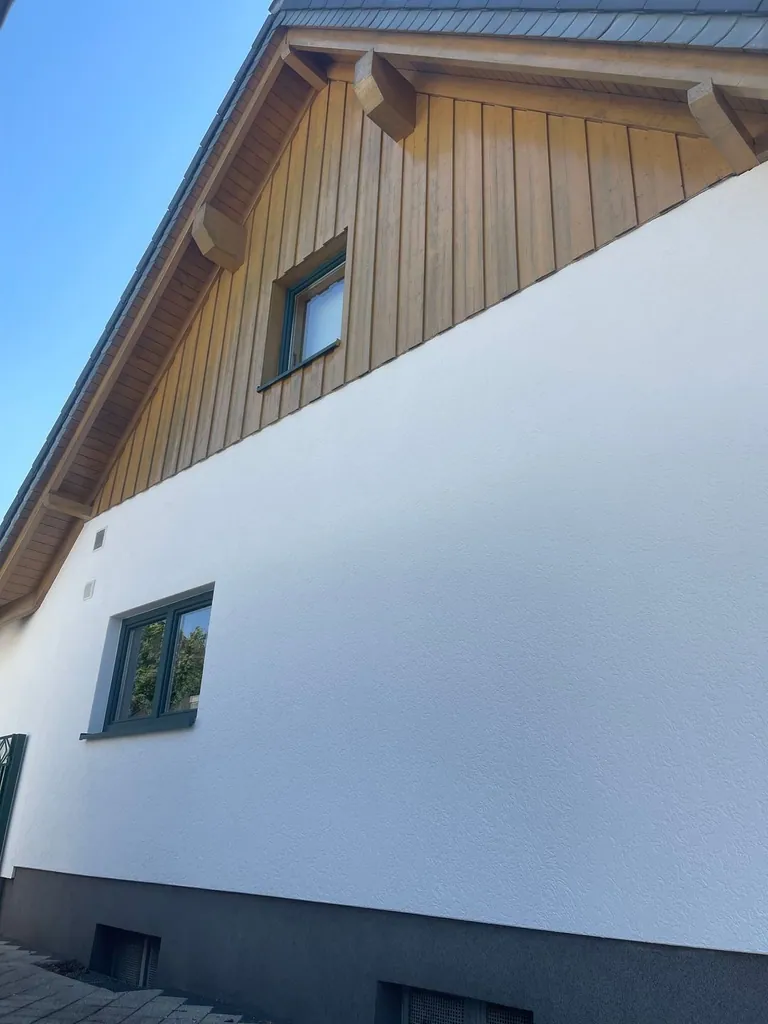 Weiß gestrichene Hausfassade mit Holzgiebel nach dem Anstrich