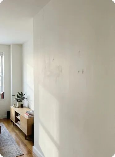 Wand vor Renovierung mit Löchern, Flecken und unebener Oberfläche im Wohnraum