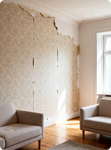 Wohnzimmer vor Tapezierung mit beschädigter Tapete und sichtbaren Rissen