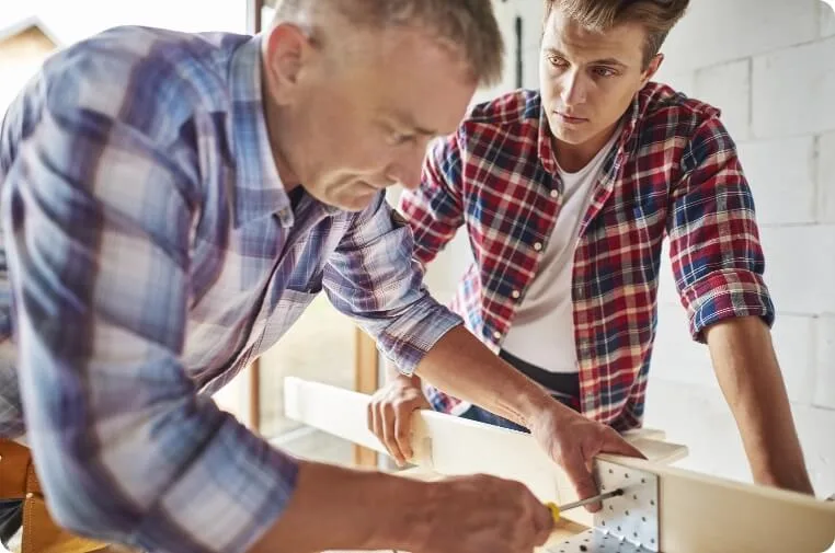 Zwei Handwerker montieren Holzbauteil gemeinsam mit Werkzeug