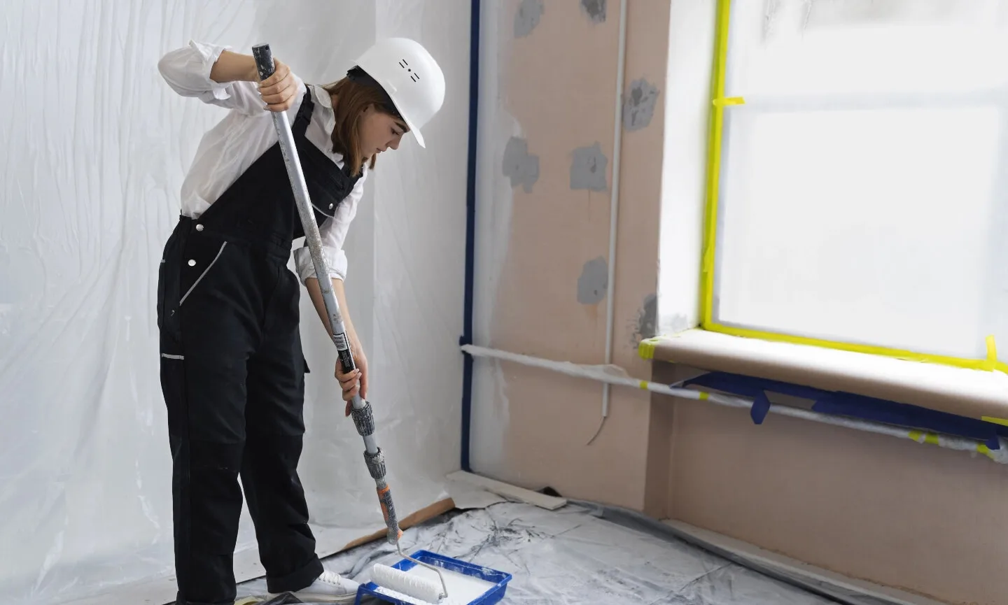 Malerin streicht Wand mit Farbrolle