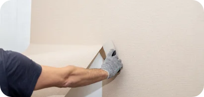 Handwerker bringt Tapete an Wand mit Glättkelle an